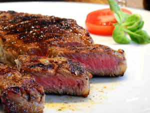 切片 medium-rare 牛扒配番茄同羅勒喺白色碟上。 — 4:3 壁紙