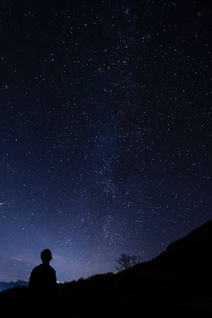 站在星空下山坡上的人