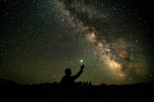 夜晚在星空下伸手的人，銀河可見