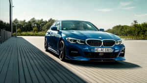 藍色BMW M3轎車停放在木質甲板上，背景有樹木和建築物。