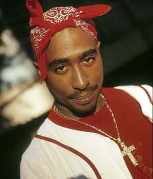 Tupac Shakur 戴著紅色頭巾和金色十字架項鍊的特寫肖像。