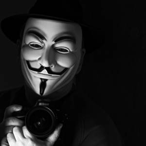 戴著蓋伊·福克斯面具的人拿著相機在黑暗環境中