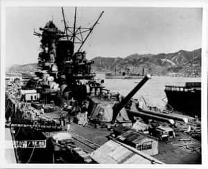 一艘大型戰艦停泊在港口，後面有山脈。 — 海 壁紙
