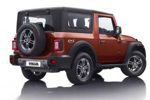 橙色Mahindra Thar SUV，後門上帶有備用輪胎，在工作室環境中