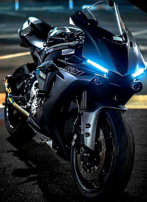 黑色Yamaha R1運動電單車在夜間濕滑的城市街道上，車頭燈閃爍。 — 機車 壁紙