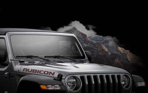 銀色Jeep Rubicon停在黑暗天空下的雪山前。