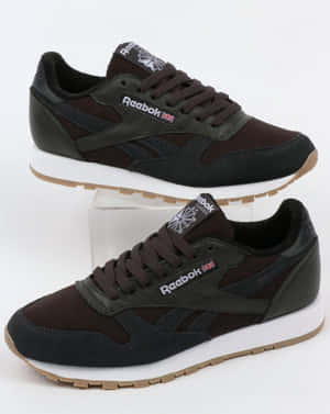 兩雙棕色和黑色的 Reebok Classic 運動鞋，白色鞋底，在攝影棚燈光下展示。 — 4:5 壁紙