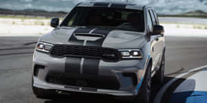 銀色Dodge Durango SRT帶有黑色賽車條紋在賽道上。