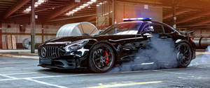 黑色 Mercedes-AMG GT R 在倉庫內飄移，伴有煙霧和警燈。 — 2560x1080 壁紙