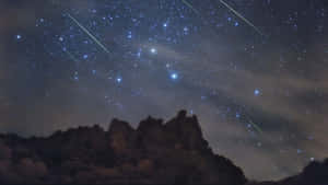 岩石山脈在星空下，有流星劃過。