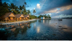 熱帶海灘茅草屋頂小屋在平靜的碧綠海水中倒映，天空暮色壯麗。
