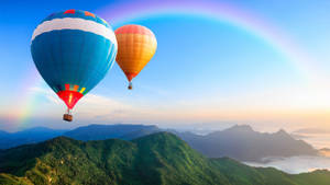 兩個熱氣球漂浮在山脈上空，天空中有彩虹。