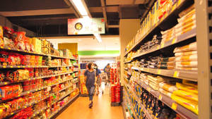 一位女士穿過充滿零食產品的超市通道。