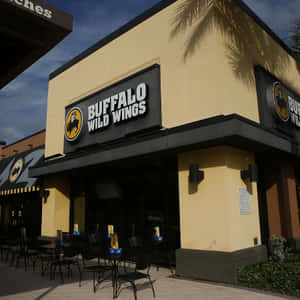 Buffalo Wild Wings 餐廳，設有戶外餐桌和棕櫚樹陰影。