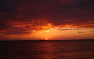 海洋上的夕陽，熾熱的紅色和橙色天空倒映在平靜的水面上。 — 天空景觀 壁紙