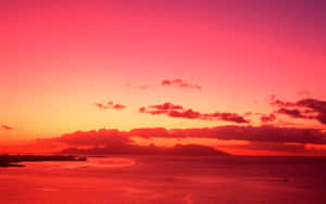 海洋上鮮豔的粉紅色和橙色夕陽，山巒剪影 — 天空美學 壁紙