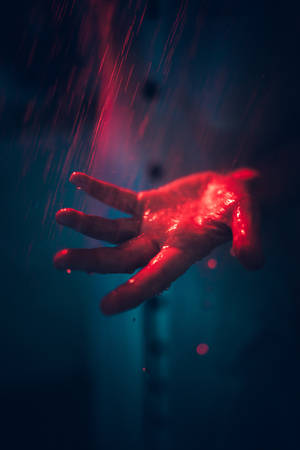 在深藍色背景的雨中，一隻發光的紅手。 — 著火 壁紙