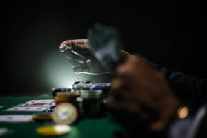 特寫鏡頭：在綠色毛氈桌上發撲克牌的手，旁邊有籌碼。