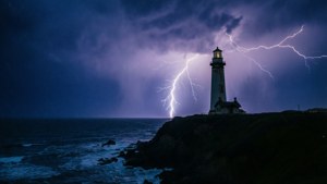暴風雨夜晚，燈塔在懸崖上被閃電照亮，海洋上方