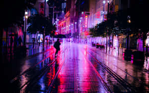 夜晚在潮濕的城市街道上，一個人在霓虹燈下獨自雨中行走。 — 日落大道 壁紙