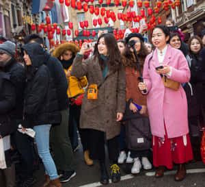 穿著冬季外套的人們在繁忙街道的紅燈籠下拍照。 — 中國新年 壁紙