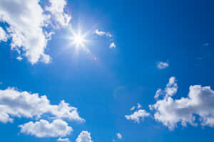 太陽穿過白雲在晴朗的藍天中閃耀。 — 藍天 壁紙