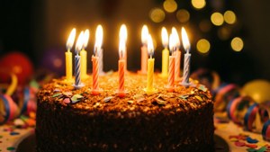 朱古力生日蛋糕，上面有點燃的蠟燭和彩色紙屑，放在節日桌上。 — 今日我生日 壁紙