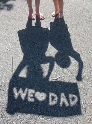 小孩的影子在行人路上用粉筆拼出「WE ❤️ DAD」。