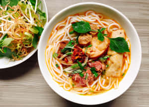 冒煙的越南河粉，牛肉、香草和辣椒，旁邊新鮮豆芽在木桌上