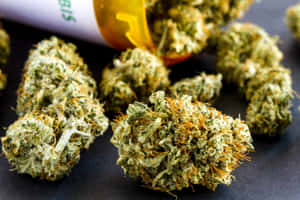 綠色大麻花蕾帶有橙色毛髮，旁邊有一個琥珀色藥瓶。 — 植物美學 壁紙
