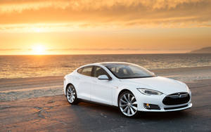 白色Tesla Model S停在金色日落的海灘上。