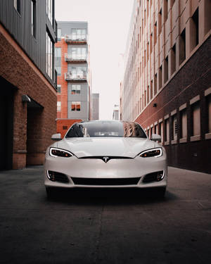 白色Tesla Model S停放在有磚砌建築的狹窄小巷中。