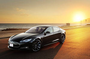 金色夕陽下，黑色Tesla汽車停泊在海邊公路上。 — Tesla GIF 壁紙