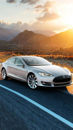 銀色Tesla Model S在金色日落時分行駛在沙漠公路上。 — Tesla GIF 壁紙
