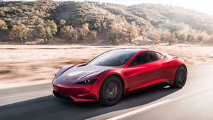一輛紅色跑車在道路上疾馳，背景有山丘。 — Tesla GIF 壁紙