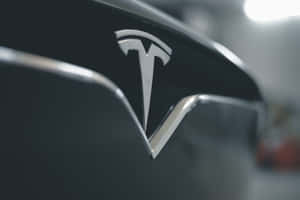 黑色車輛上閃亮的 Tesla 徽章，背景燈光模糊。