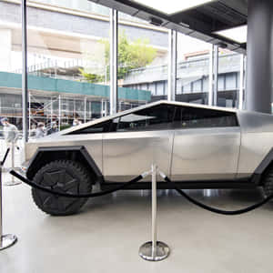銀色Tesla Cybertruck在天鵝絨繩索和旁觀者陪同下於玻璃建築中展示。