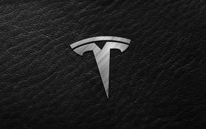 黑色皮革表面上的 Tesla 標誌 — Tesla GIF 壁紙