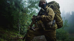 一名身穿迷彩服的士兵在霧氣瀰漫的森林中蹲下，握著步槍。 — 軍事動圖 壁紙