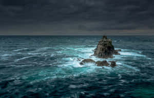 暴風雨的海面，海浪拍打著孤獨的岩石島嶼。 — 海浪 壁紙
