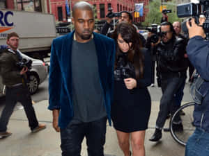 Kanye West 和 Kim Kardashian 在媒體包圍下走過城市街道。