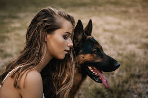 女性與德國牧羊犬在草地上共享寧靜時刻。