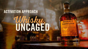 酒吧上的Monkey Shoulder威士忌瓶，帶有「Whisky Uncaged」文字和溫暖燈光。