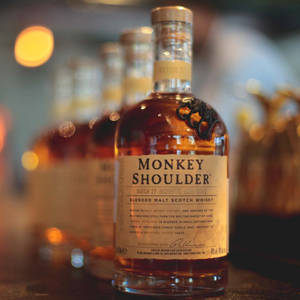 在昏暗的酒吧中，帶有散景燈光的 Monkey Shoulder 威士忌酒瓶。
