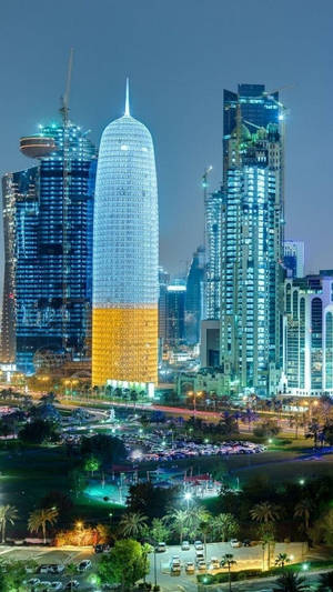 夜晚的城市景觀，有燈火通明的摩天大樓和棕櫚樹。 — 建築 壁紙