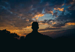 一個人企喺剪影中，觀賞色彩繽紛嘅日落天空。