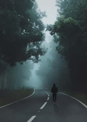 黃昏時分，有人在霧氣瀰漫的樹林道路上奔跑。