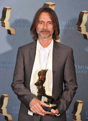 男子身穿西裝在活動中手持 Gemini Award 獎座。 — 亞當·布羅迪 壁紙