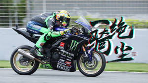賽車手騎著Yamaha電單車在賽道上傾斜入彎，帶有Monster Energy品牌標誌。