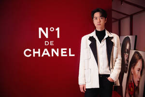 男子穿著 Chanel 外套在紅色背景和品牌文字的攝影棚中擺姿勢。 — 成振宇 壁紙